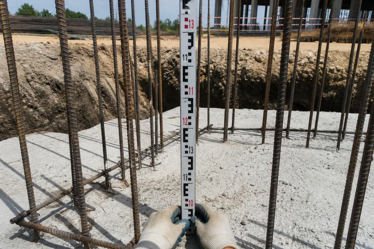 Mire graduée tenue à la verticale sur une semelle de fondation en attente de coulage